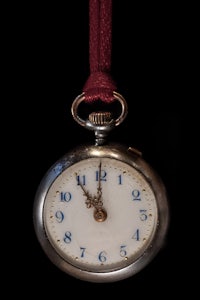 a silver pocket watch hanging on a red cord